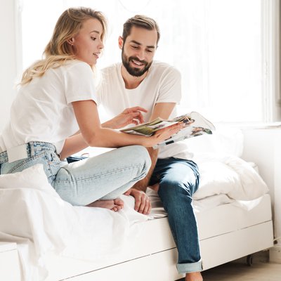 Pärchen sitzt auf einer Couch und blättert in einem Magazin, Vorsetllung der neuen Trends ums Thema wohnen